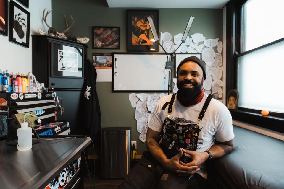 Artist Adrien Clark sits in his former office that was converted to a tattoo room to make space for other artist in his shop on Alexander Street.