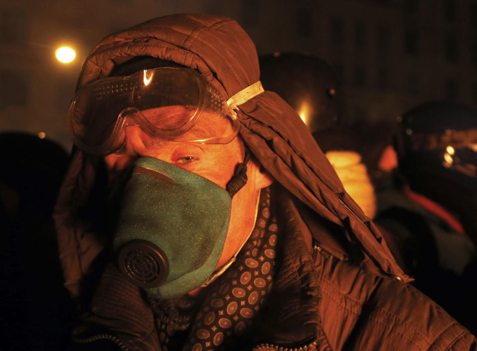 A protester warms himself behind the barricade in central Kiev, Ukraine, early Friday Jan. 24, 2014. A top Ukrainian opposition leader on Thursday urged protesters to maintain a shaky cease-fire with police after at least two demonstrators were killed in clashes this week, but some in the crowd appeared defiant, jeering and chanting "revolution" and "shame." (AP Photo/Sergei Grits)
