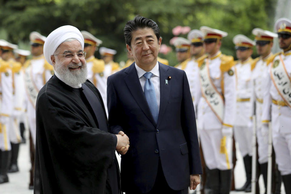 Japanese Prime Minister Shinzo Abe, center, shakes hands for the cameras with Iranian President Hassan Rouhani, during the official arrival ceremony, at the Saadabad Palace in Tehran, Iran, Wednesday, June 12, 2019. The Japanese leader is in Tehran on a mission to calm tensions between the U.S. and Iran. (AP Photo/Ebrahim Noroozi)