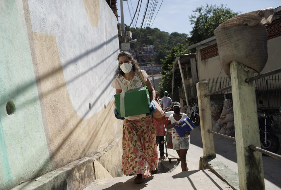 La directora de la agrupación Mano en la Yaca, Marisa Furtado, lleva cajas con semillas de yaca a la "Favela Orgánica" de un barrio pobre de Río de Janeiro el 11 de febrero del 2021. (AP Photo/Silvia Izquierdo)