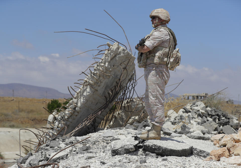 Russian military police officer stands guard near the town of Alhureyeh, Syria, Tuesday, Aug. 14, 2018. The Russian military said Tuesday that its forces in Syria will help U.N. peacekeepers fully restore patrols along the frontier with the Israeli-occupied Golan Heights, reflecting Moscow's deepening role in mediating between the decades-old foes. (AP Photo/Sergei Grits)