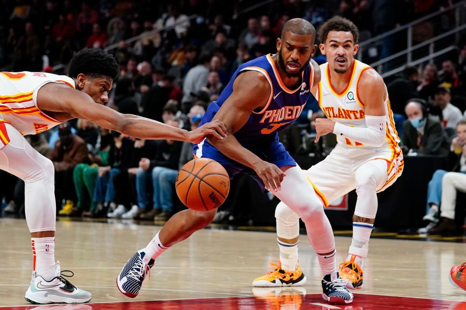 Phoenix Suns guard Chris Paul (3) drives between Atlanta Hawks' Trae Young (11) and De'Andre Hunter (12) during the first half of an NBA basketball game Thursday, Feb. 3, 2022, in Atlanta. (AP Photo/John Bazemore)