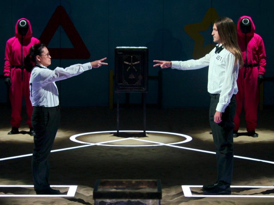 Mai Whelan and Phill Cain in formal clothing showing scissors hand signal to each other in "Squid Game: The Challenge"