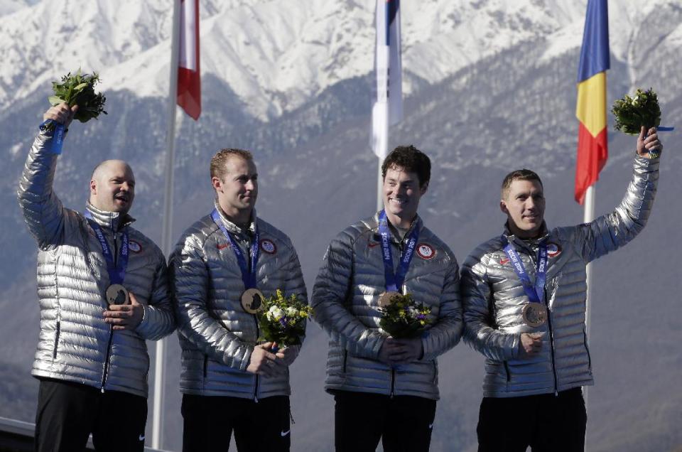 The team from the United States USA-1, with Steven Holcomb, Curtis Tomasevicz, Steven Langton and Christopher Fogt, wave after they received their bronze medals during the men's four-man bobsled competition final at the 2014 Winter Olympics, Sunday, Feb. 23, 2014, in Krasnaya Polyana, Russia. (AP Photo/Michael Sohn)