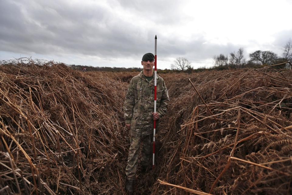 British army Rifleman Stuart Gray, holding a pole to measure the height, walks on a WW1 practise trench as he poses for the photographers in Gosport, southern England, Thursday, March 6, 2014. This overgrown and oddly corrugated patch of heathland on England’s south coast was once a practice battlefield, complete with trenches, weapons and barbed wire. Thousands of troops trained here to take on the Germany army. After the 1918 victory _ which cost 1 million Britons their lives _ the site was forgotten, until it was recently rediscovered by a local official with an interest in military history. Now the trenches are being used to reveal how the Great War transformed Britain _ physically as well as socially. As living memories of the conflict fade, historians hope these physical traces can help preserve the story of the war for future generations. (AP Photo/Lefteris Pitarakis)