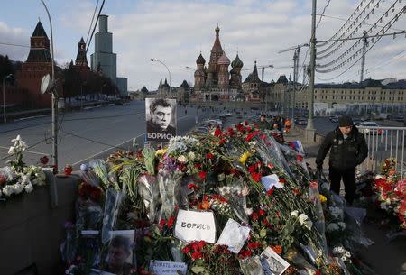 A man walks past flowers at the site where Kremlin critic Boris Nemtsov was murdered on February 27, at the Great Moskvoretsky Bridge, with St. Basil's Cathedral seen in the background, in central Moscow March 6, 2015. REUTERS/Maxim Shemetov