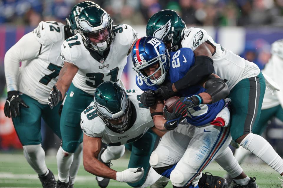 Jan 7, 2024; East Rutherford, New Jersey, USA; New York Giants running back Saquon Barkley (26) is tackled by Philadelphia Eagles linebacker Nicholas Morrow (41) and linebacker Patrick Johnson (48) and safety Kevin Byard (31) during the second half at MetLife Stadium. Mandatory Credit: Vincent Carchietta-USA TODAY Sports