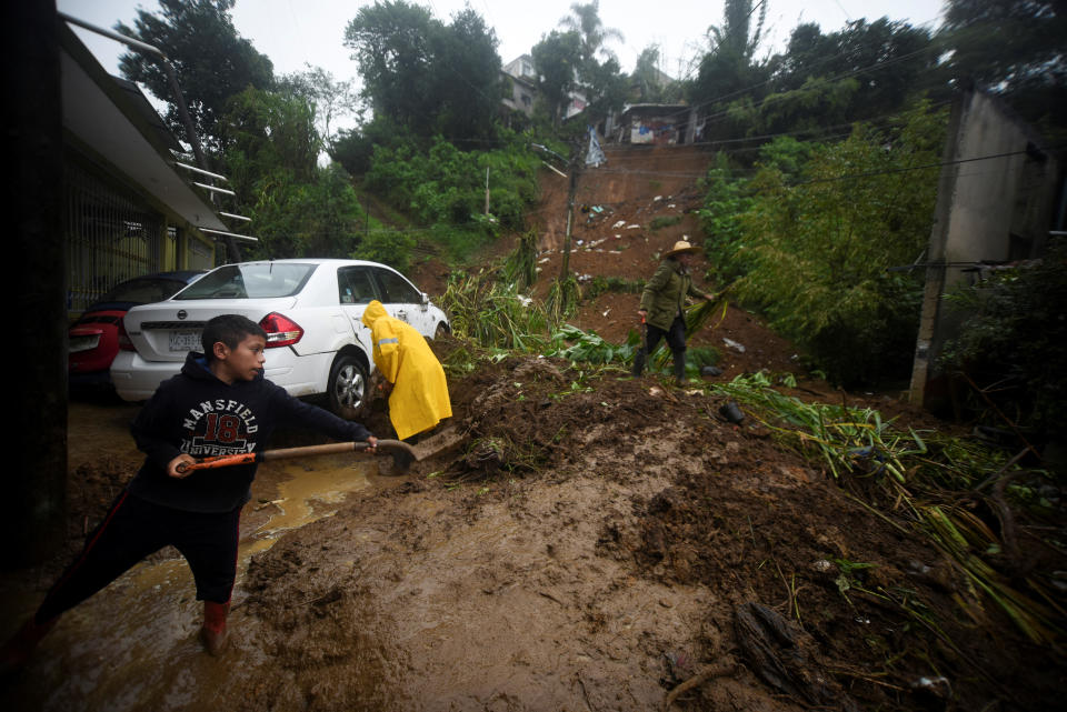 Varios residentes, entre ellos un niño, ayudan a remover el lodo de un carro parcialmente dañado por los deslaves generados por la tormenta Chris, en Xalapa / REUTERS/Oscar Martinez