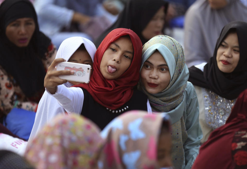 <p>Diese zwei jungen Muslima in Indonesien nutzen die Zeit vor dem Morgengebet für ein schnelles Selfie. (Bild: AP Photo/ Dita Alangkara) </p>