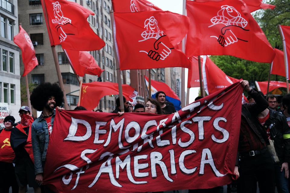 Young crowd of young people holding red 'DSA' banners on a New York street