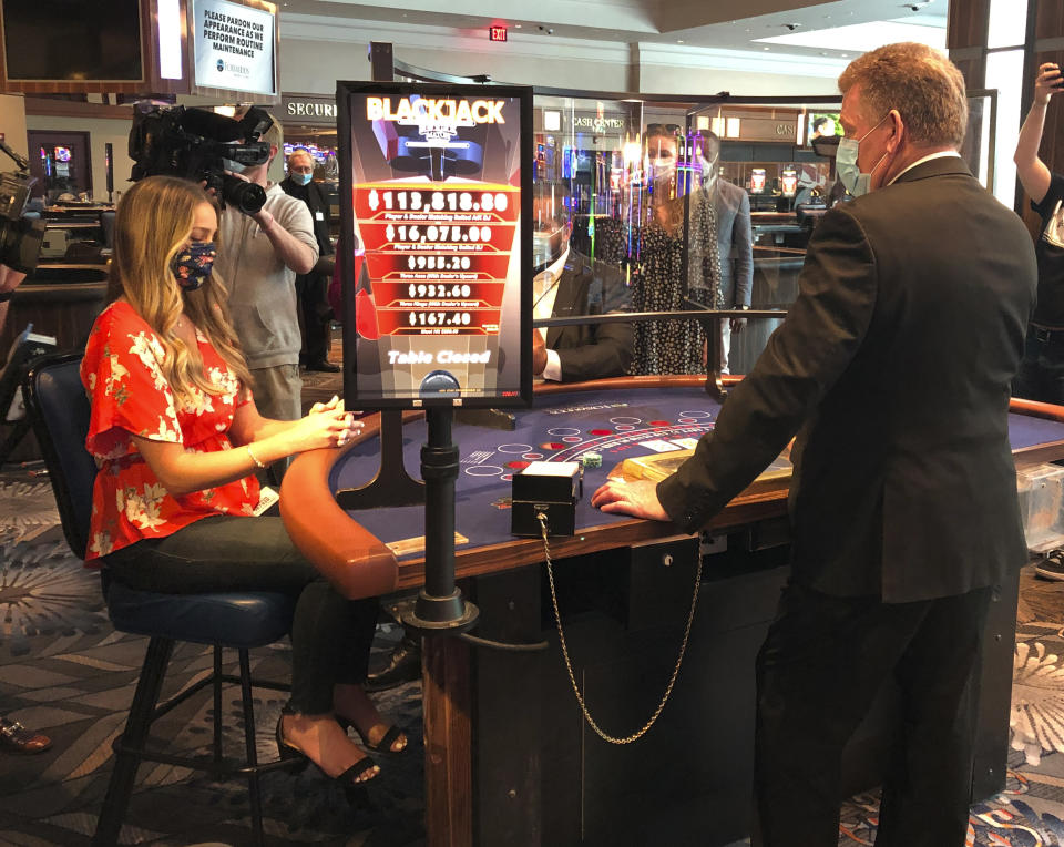 In this May 22, 2020 photo, a blackjack dealer at Foxwoods Resort Casino in Mashantucket, Conn., demonstrates to reporters on how new protective measures, including plastic shields, will work when the tribal-owned Foxwoods and neighboring Mohegan Sun expect to partially reopen on June 1. The Mashantucket Pequot and Mohegan Tribes are pushing ahead with plans to open their resorts on tribal lands, despite opposition from Connecticut Gov. Ned Lamont. (AP Photo/Susan Haigh)