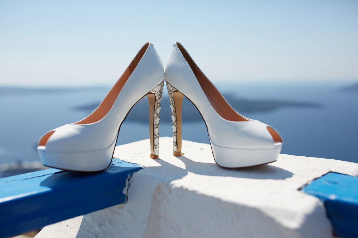 high heel shoes are on the railing overlooking the sea and clear blue sky
