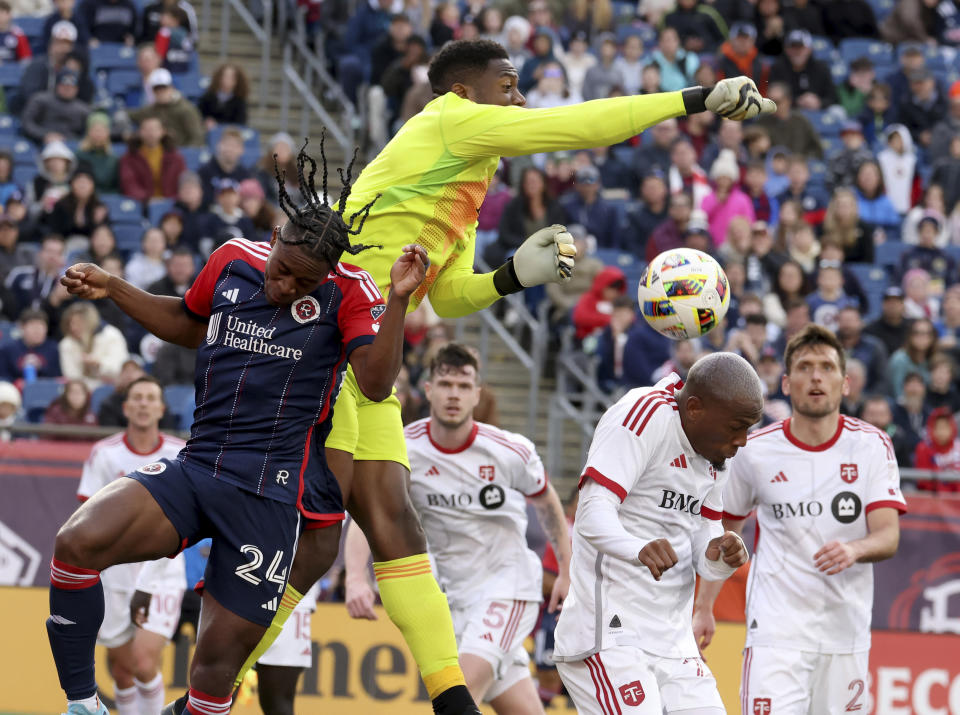 Toronto FC goalkeeper Sean Johnson punches the ball over New England Revolution defender Nick Lima (24) while defending the net in the second half of an MLS soccer match, Sunday, March 3, 2024, in Foxborough, Mass. (AP Photo/Mark Stockwell)