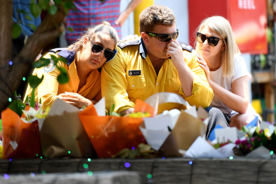 Two members of the Horsley Park RFS and another woman are seen at a memorial for firefighters at the Horsley Park Rural Fire Brigade.