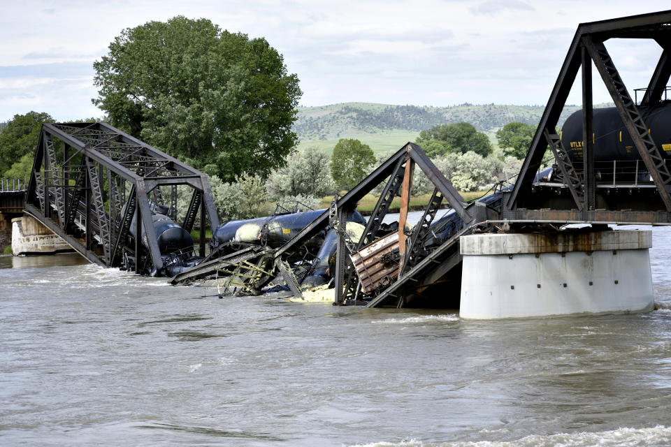 Several train cars are immersed in the Yellowstone River after a bridge collapse near Columbus, Mont., on Saturday, June 24, 2023. The bridge collapsed overnight, causing a train that was traveling over it to plunge into the water below. Authorities on Sunday were testing the water quality along a stretch of the Yellowstone River where mangled cars carrying hazardous materials remained after crashing into the waterway. (AP Photo/Matthew Brown)