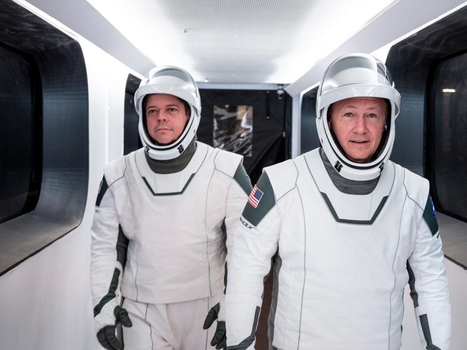 In this Jan. 17, 2020 photo made available by SpaceX, NASA astronauts Bob Behnken, left, and Doug Hurley, wearing SpaceX spacesuits, walk through the Crew Access Arm connecting the launch tower to the SpaceX Crew Dragon spacecraft during a dress rehearsal at NASA's Kennedy Space Center in Cape Canaveral, Fla. For their May 27, 2020 mission, Hurley will be in charge of launch and landing and Behnken will oversee rendezvous and docking at the International Space Station. (SpaceX via AP)