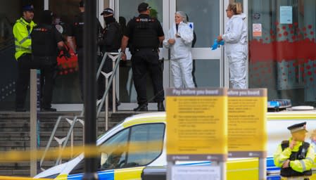 Police forensic officers stand with armed officers outside the Arndale shopping centre after several people were stabbed in Manchester, Britain