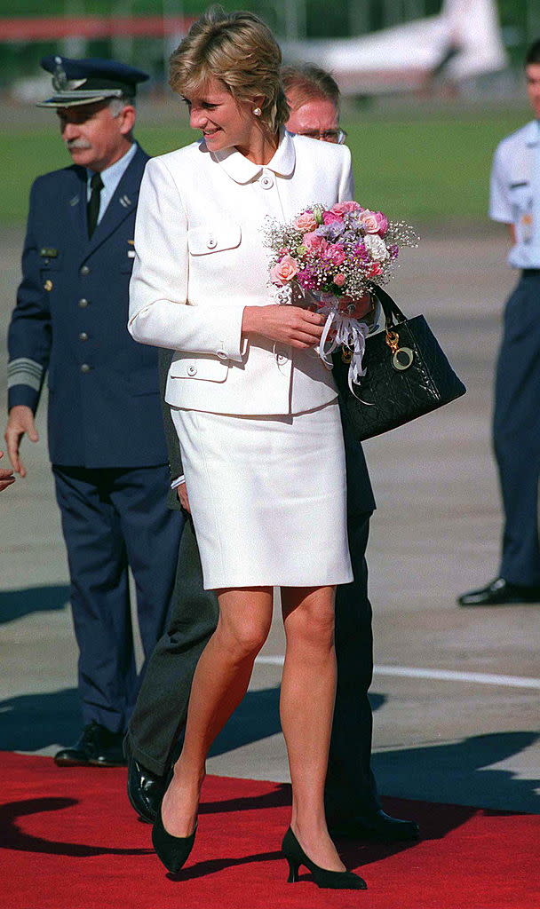 Princess Diana Arriving At Buenos Aires Airport For Her Historic Visit To Argentina. The Princess Is Wearing A White Suit Designed By Fashion Designer Versace And She Is Carrying A Black Christian Dior Handbag.