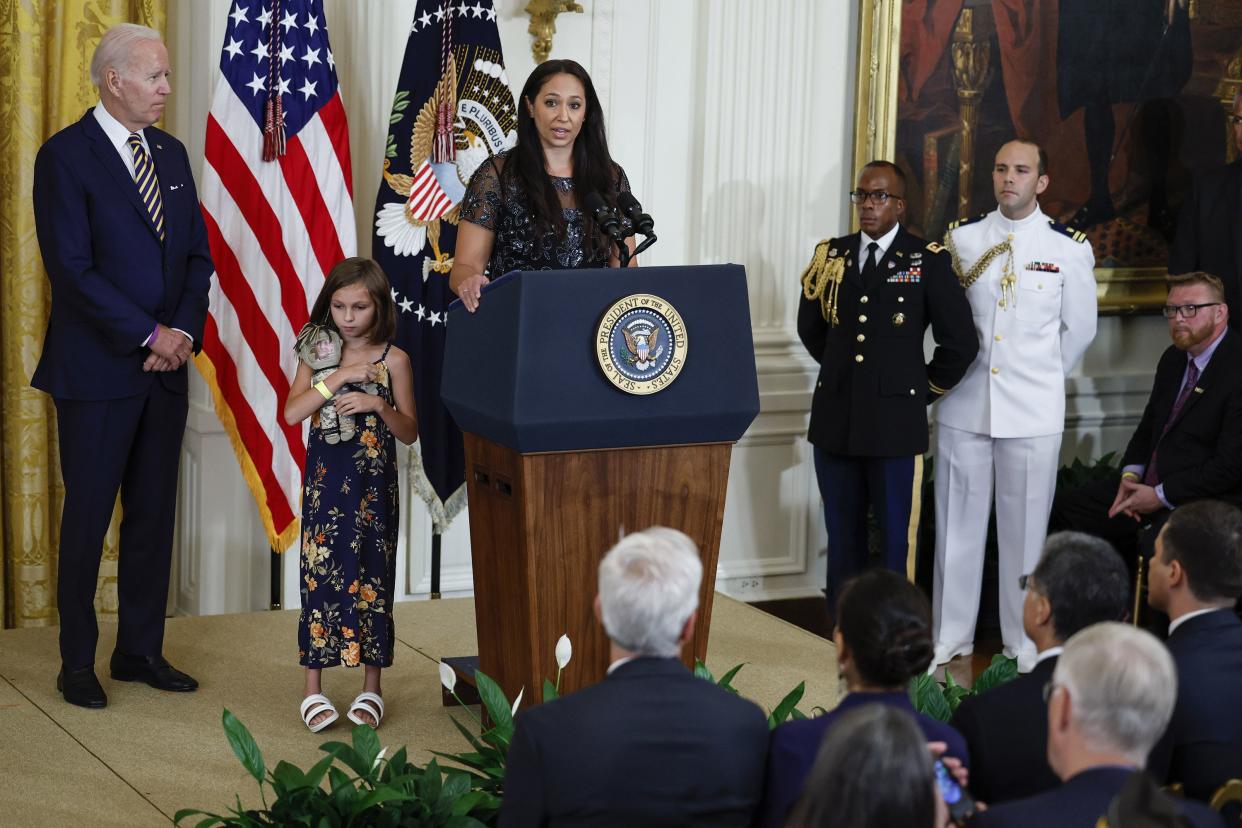 (L-R) U.S. President Joe Biden and Brielle Robinson, daughter of the late Sgt. First Class Heath Robinson, look on as Danielle Robinson, widow of Sgt. First Class Heath Robinson, speaks during a signing ceremony for The PACT Act in the East Room of the White House on Aug. 10, 2022, in Washington, DC. The bill is the biggest expansion of veteran's benefits since the Agent Orange Act of 1991 and will expand health care benefits to millions of veterans exposed to toxic substances during their military service.