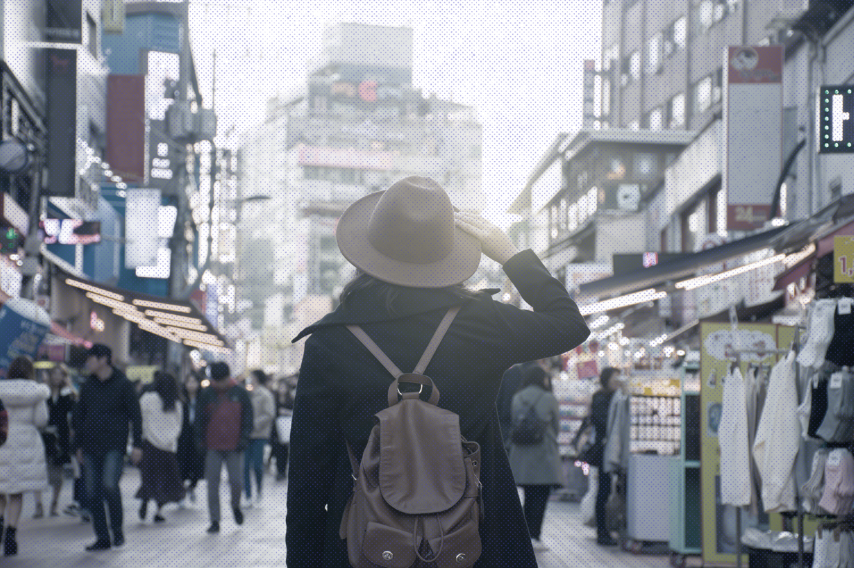 a person wearing a fedora and a backpack looking into the city