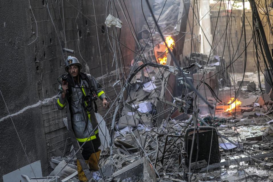 A Palestinian firefighter works at the site of a destroyed building (EPA)