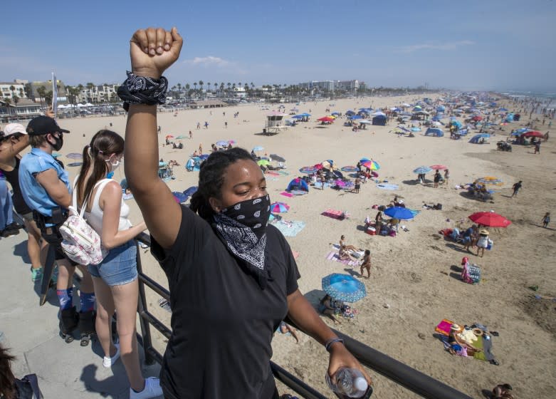 HUNTINGTON BEACH, CA - SEPTEMBER 06: Black Lives Matter supporter Mari Drake, of Los Angeles, raises her fist in the air as she joins protesters marching down the Huntington Beach pier in protest of justice for George Floyd and against the deaths of numerous other African Americans by police actions in Pier on Sunday, Sept. 6, 2020 in Huntington Beach, CA. Members of the groups Black Unity, Dope Movement also participated to show support for Queer Black Lives and All Black Lives Matter. (Allen J. Schaben / Los Angeles Times)