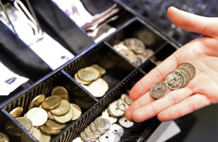 A waitress poses with some coins in front of a cash-box of Danish crowns in a pub in Copenhagen, January 22, 2015. REUTERS/Fabian Bimmer