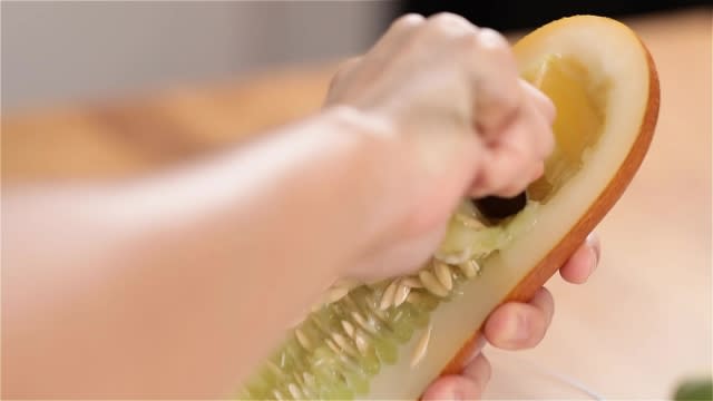 Scraping out old cucumber seeds with a spoon