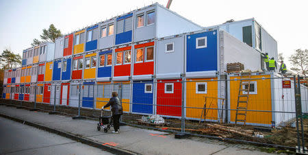 FILE PHOTO - Workers fix containers at a construction site for a refugee centre to house asylum seekers in the Koepenick district of Berlin, Germany November 27, 2014. REUTERS/Hannibal Hanschke/File Photo