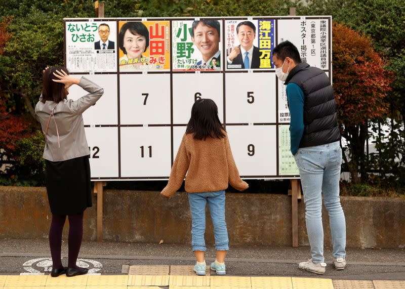 Voters look at posters of candidates for a lower house election, amid the coronavirus disease (COVID-19) pandemic, outside a polling station in Tokyo