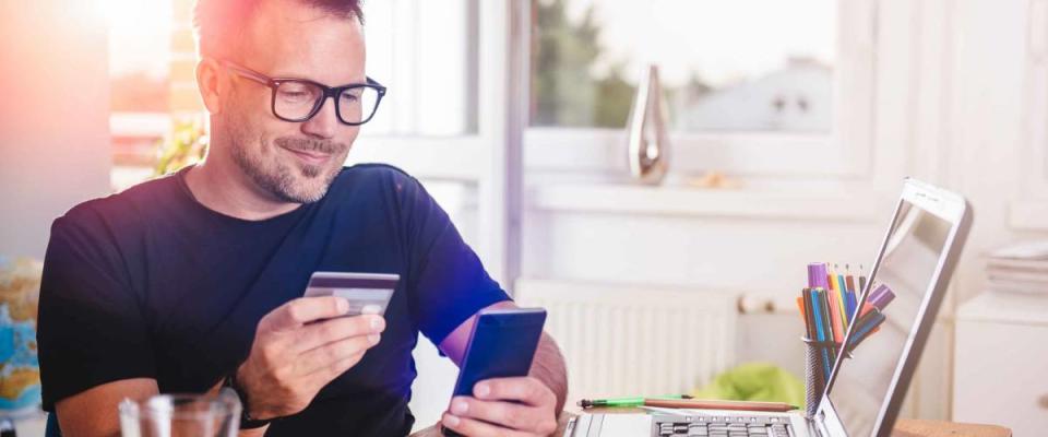 Man paying with credit card on smart phone at home office