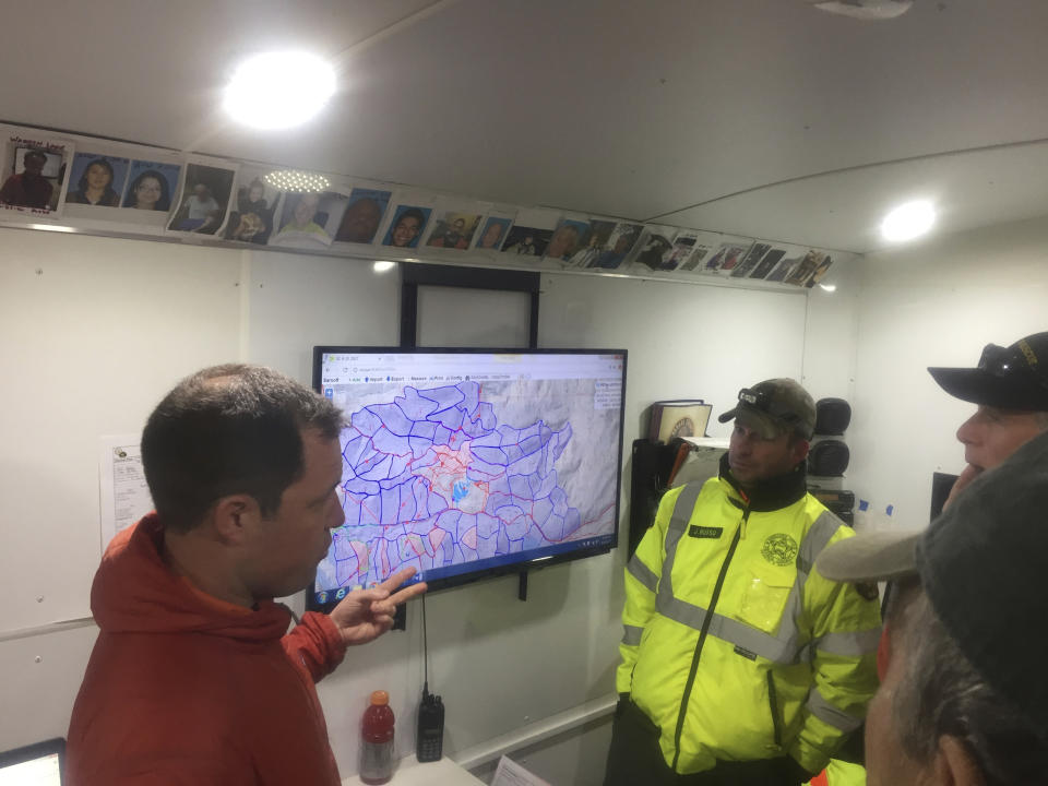 This April 17, 2017, photo provided by Michael St. John shows search and rescue volunteer and SARTopo creator Matt Jacobs, left, and search and rescue volunteers Mike Russo, center, and Bob Gehlen, right, in Sierraville, California, as they consult a SARTopo map while making plans to search for a missing aircraft. The dramatic rescue of a hiker lost for more than two weeks in a remote Hawaii forest is showing how emerging technology is helping search teams more efficiently scour the wilderness for missing people. (Michael St. John/Marin County Sheriff's SAR unit via AP)