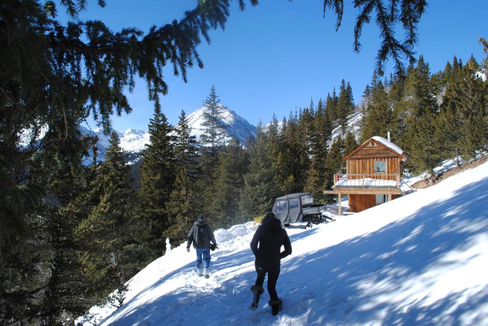 In this Jan. 24, 2014 photo, Andy and Ceil Barrie walk to their mining cabin near Breckenridge, Colo. Summit County wants to condemn 10 acres of land that belongs to the Barrie's through the controversial power of eminent domain. (AP Photo/Nicholas Riccardi)