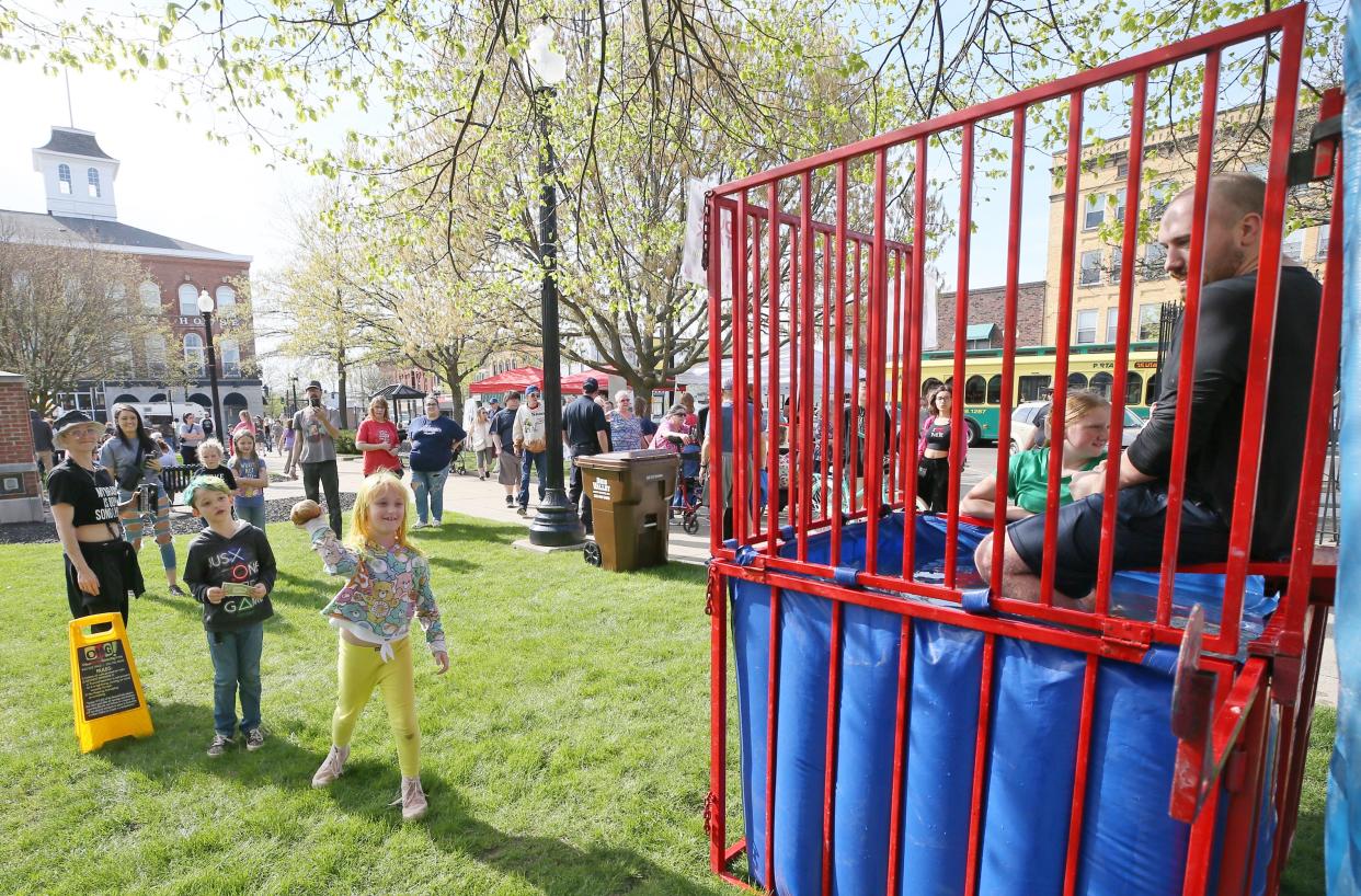 Negan Cross, 7, watches as his sister Liberty, 8, takes a turn in trying to dunk Stephen Delciappo, a 12th-grade English teacher at Ravenna High School, during the Ravenna Jo-Jo Festival on Friday.