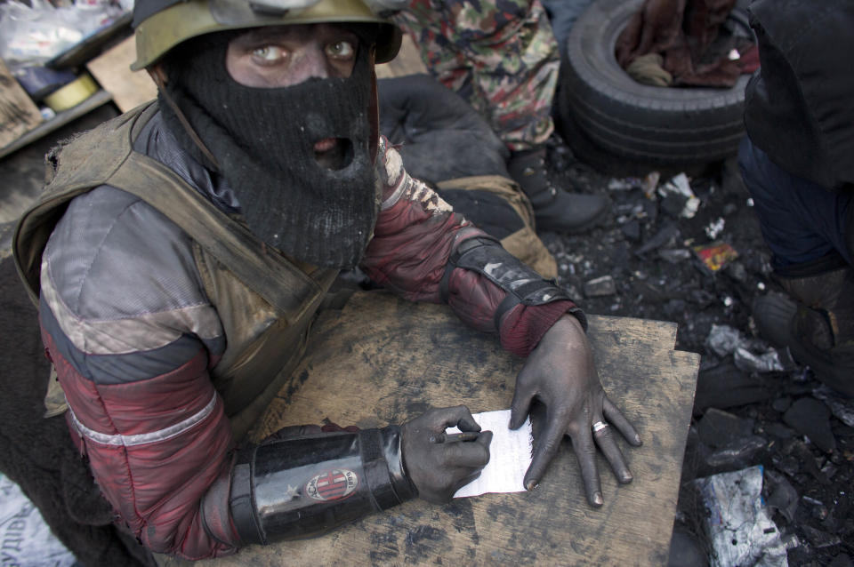 An anti-government activist with his hands tinted with soot from burning tires makes notes at a barricade in central Kiev, Ukraine, Friday, Jan. 31, 2014. Negotiations between the authorities and the opposition on finding a way out of the crisis appeared to have stalled on Thursday, after Yanukovych took an unexpected sick leave and told opposition leaders that it was now up to them to make concessions. (AP Photo/Darko Bandic)