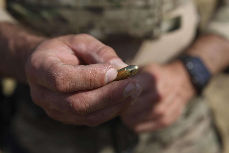 Polish instructor, Dariusz Tomysek, shows a pistol bullet during a practice for Belarusian volunteers at a shooting range near Warsaw, Poland, on Friday, May 20, 2022. (AP Photo/Michal Dyjuk)