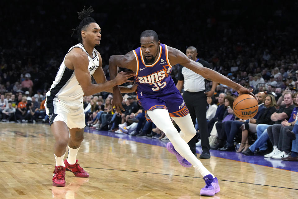 Phoenix Suns forward Kevin Durant (35) drives on San Antonio Spurs guard Devin Vassell during the first half of an NBA basketball game Thursday, Nov 2, 2023, in Phoenix. (AP Photo/Rick Scuteri)