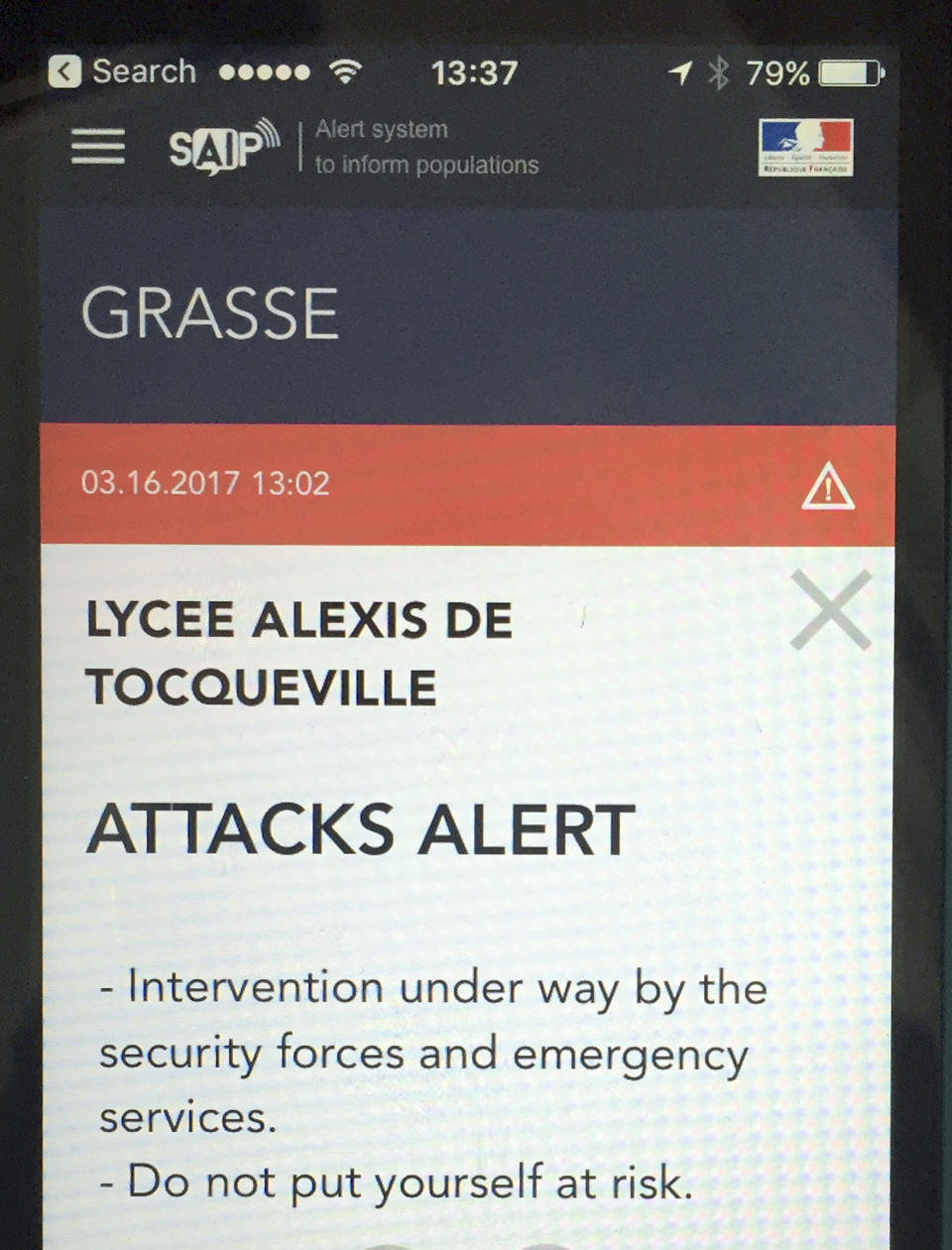 A French police message alert is displayed on a cell phone in Paris, France, Thursday, March 16, 2017. The French government has sent out an alert warning of an attack at the Alexis de Tocqueville high school in the southern French town of Grasse after local police reported that shots have been fired. (AP Photo)