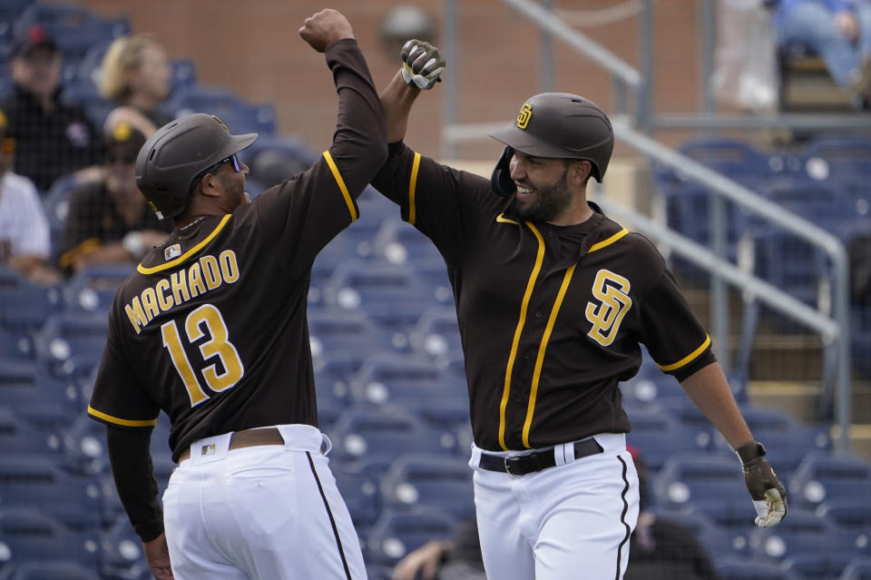 San Diego Padres Eric Hosmer, right, celebrates his home run with teammate Manny Machado (13) in the fourth inning of a spring training baseball game against the Cleveland Indians, Thursday, March 11, 2021, in Peoria, Ariz. (AP Photo/Sue Ogrocki)