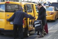 A taxi driver helps a traveler with his suitcase, Wednesday, Jan. 29, 2020, in New York. A task force studying New York City's struggling taxi industry called Friday for “mission-driven” investors to help bail out drivers who incurred massive debt once the value of the medallion that allows a person to operate a yellow cab plummeted in the age of Uber and Lyft. (AP Photo/Mark Lennihan)