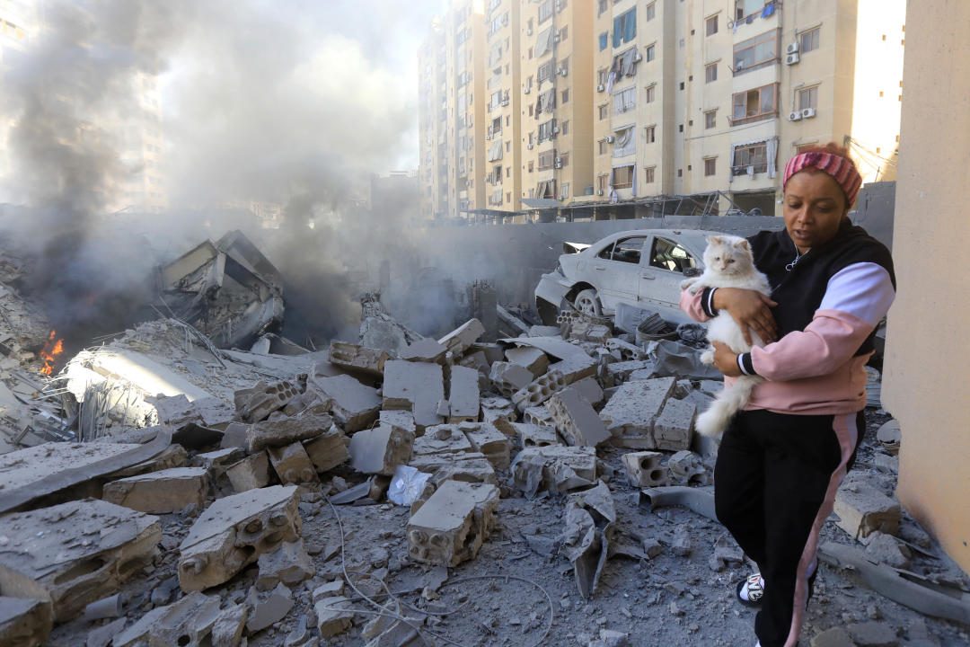 Una mujer con un gato junto a un edificio destruido en el lugar de un ataque aéreo israelí nocturno en el suburbio de Shayyah, al sur de Beirut, el 2 de octubre de 2024. Al menos cinco ataques israelíes alcanzaron los suburbios del sur de Beirut este 2 de octubre, dijo una fuente de seguridad libanesa, mientras que el ejército israelí dijo que estaba apuntando a sitios de Hezbollah y emitió varias órdenes de evacuación. (Foto de AFP) (Foto de -/AFP vía Getty Images)