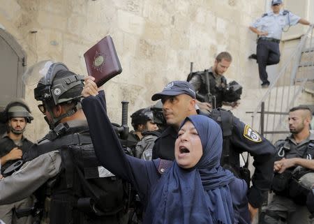 A Palestinian woman shouts slogans as she holds a Koran during clashes with Israeli police forces in Jerusalem's Old City September 14, 2015. REUTERS/Ammar Awad