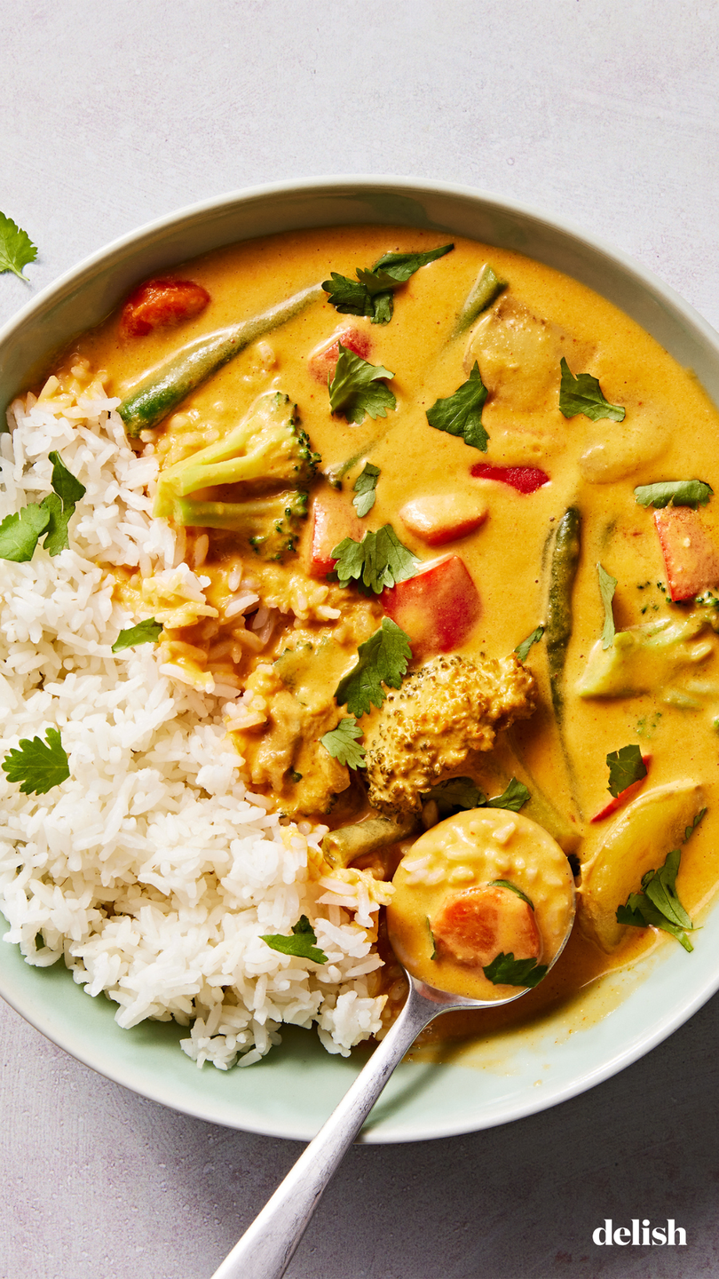 a bowl of rice with a coconut milk based curry sauce, broccoli, green beans, carrots, potatoes and bell peppers