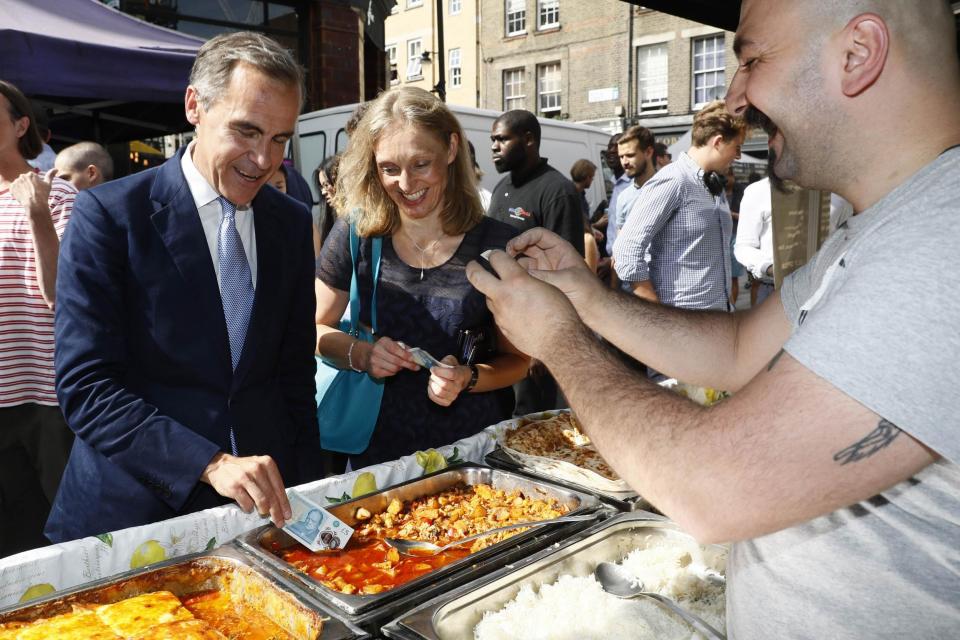 Lean looking: Bank Governor Mark Carney tests polymer £5 note at Whitecross Street Market: Getty Images