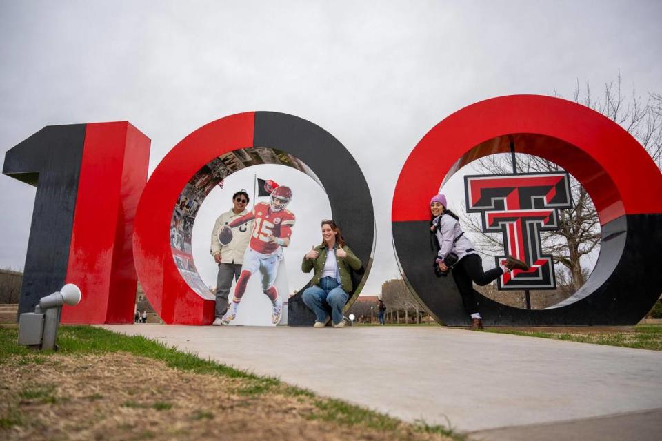 Journalists Emily Curiel, left, Irvin Zhang, and Alison Booth pose for a photo next to the Texas Tech University 100th anniversary sculpture alongside a life-size cutout featuring Kansas City Chiefs quarterback Patrick Mahomes at Texas Tech University.