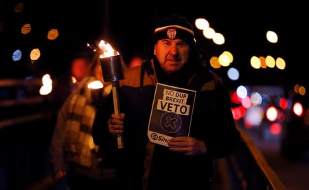 A man holds a placard as he attends a candlelight vigil on the border between Ireland's Donegal county and Londonderry county in Northern Ireland in Lifford, Ireland