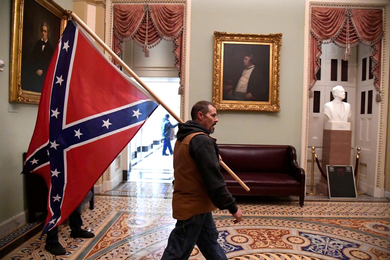 <p>A pro-Trump rioter carries a Confederate flag through the halls of the Capitol on Wednesday</p> (REUTERS)