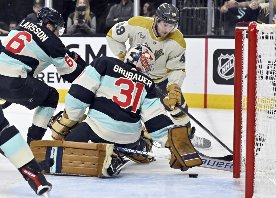 Seattle Kraken defenseman Adam Larsson (6) and goaltender Philipp Grubauer (31) defend the net against Vegas Golden Knights center Ivan Barbashev (49) during the second period of an NHL hockey game Thursday, March 21, 2024, in Las Vegas. (AP Photo/David Becker)