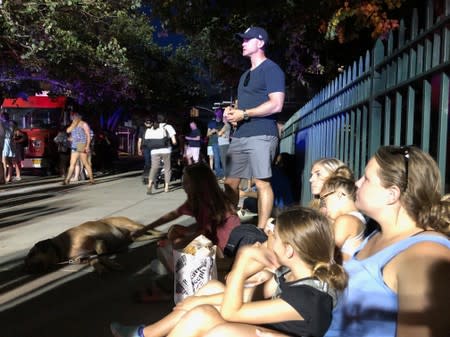 Residents watch policemen and firemen gather at their apartment building as a blackout affects buildings during widespread power outages in the Manhattan borough of New York