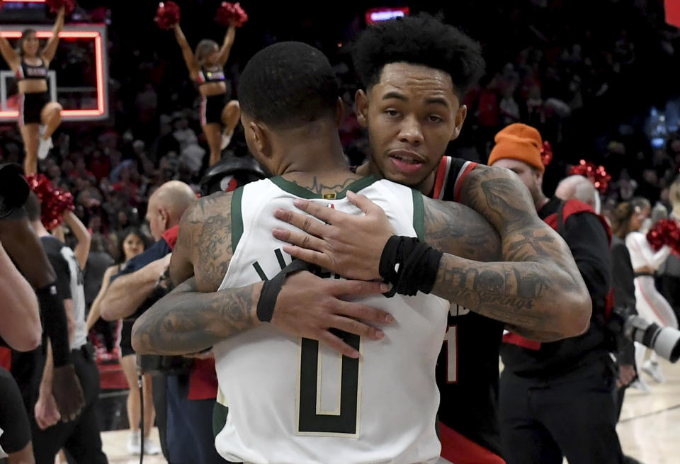 Milwaukee Bucks guard Damian Lillard (0) hugs Portland Trail Blazers guard Anfernee Simons after an NBA basketball game in Portland, Ore., Wednesday, Jan. 31, 2024. (AP Photo/Steve Dykes)